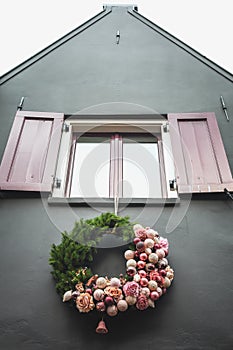 Christmas wreath hanging under a window of a house