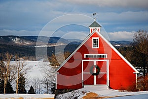 A Christmas wreath hangs on a red barn