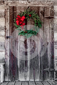 Christmas wreath hung on a rustic log cabin door