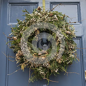 Christmas wreath made of pine and juniper, decorated with dry poppy heads, herbs, berries in green and brown tones on the front