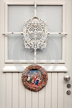 Christmas wreath made of plaster with Christmas scene attached to a white door of a house