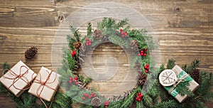 Christmas wreath made of spruce branches with gifts on wooden board. Flat lay. Top view.