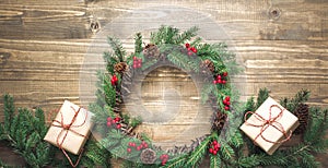 Christmas wreath made of spruce branches with gifts on wooden board. Flat lay. Top view.