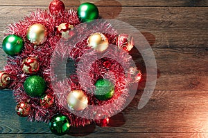 Christmas wreath of red garlands and Christmas toys on the background of a wooden table. Merry Christmas and happy holidays. View