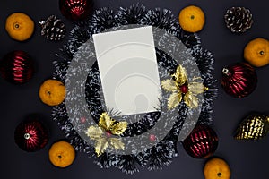 Christmas wreath, red and gold fir tree decor and tangerines on black background. Blank card with text place