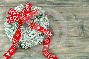 Christmas wreath with red ribbon bow on wooden background