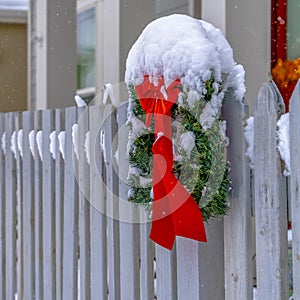 Christmas wreath with red ribbon on picket fence