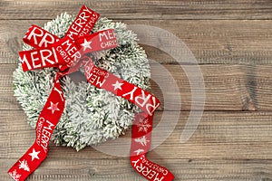 Christmas wreath with red ribbon on wooden background