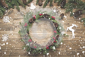 Christmas wreath of spruce branches with holly berries on wooden board. Flat lay. Top view.