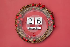 Christmas wreath and wooden calendar with date December 26 on red background Boxing Day occurs annually on December 26