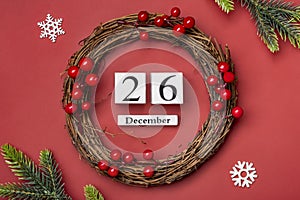 Christmas wreath and wooden calendar with date December 26 on red background Boxing Day occurs annually on December 26