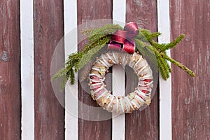 christmas wreath on wooden door fastened in ring and used for decoration with red bow