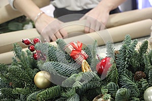 Christmas wrest with baubles and Woman wrapping modern Christmas gifts presents defocused