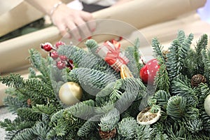 Christmas wrest with baubles and Woman wrapping modern Christmas gifts presents defocused