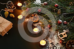 Christmas. Xmas toys, burning candles and spruce branch on black background top view. Space for text