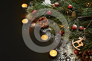 Christmas. Xmas toys, burning candles and spruce branch on black background top view. Space for text