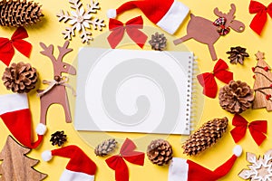 Christmas yellow background with holiday toys and decorations. Top view of notebook. Happy New Year concept