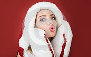 Christmastime. Sexy Christmas girl in fur hat and white gloves sending air kiss. Winter holidays celebration. Beautiful