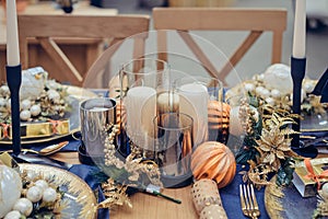 Christmastime table setting, festive dinnerware decorated with pretty details and candles in Blue and Gold colors. Navy Blue Table