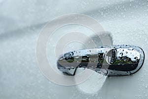 Chrome car door handle and shiny white surface with water droplets and negative space for copy