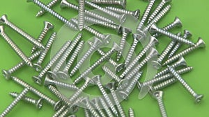 Chrome crosshead screws rotating on a green background.