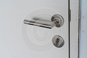 Chrome door handle and lock with key on white door