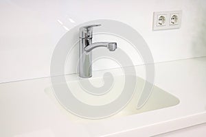 Chrome faucet with white sink in the bathroom