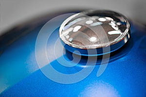 Chrome gas tank cap on blue motorcycle