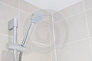 Chrome modern shower head and neutral tiles in bathroom ensuite