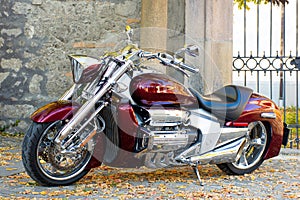 Chrome motorcycle parked by a stone fence, autumn landscape