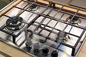 Chrome plate of gas cooker. Four control knobs. Kitchenware.