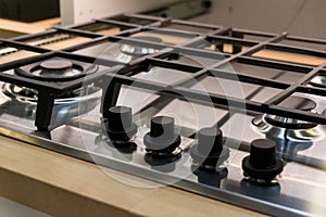 Chrome plate of gas cooker. Four control knobs. Kitchenware.