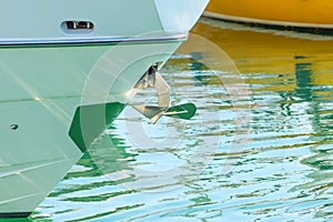 Chrome-plated metal anchor on the bow of the boat in the bay