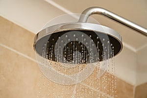 Chrome shower head with water droplets. Increasing water bills.