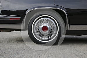 Chrome wheel with silvery spokes and a new rubber on a black shiny Cadillac