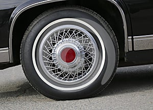 Chrome wheel with silvery spokes and a new rubber on a black shiny Cadillac