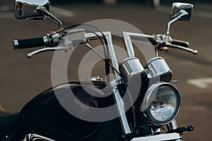 Chromed motorcycle handlebars and headlights, close-up Stylish custom chopper motobike with chrome details. Soft selective focus