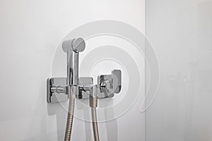 Chromium bidet shower with white tiles in a toilet. Clean and new spray shower