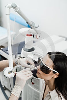 Chronic rhinitis treatment with laser. ENT doctor in protective glasses holding surgical laser and doing laser treatment