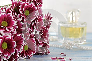chrysanthemum and perfume in the background on a blue wooden table