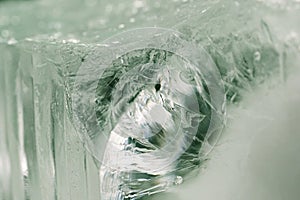 Chrystal clear frosty textured natural ice block in cold light green tones, isolated on black background