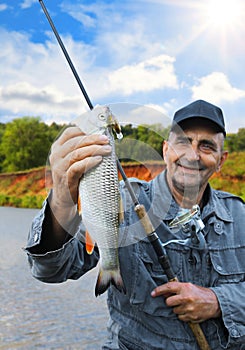 Chub in the hand of fisherman against the sky and the river