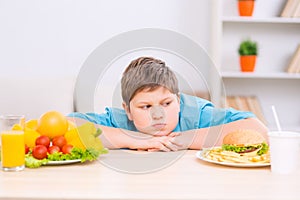 Chubby boy is looking at junk food plate