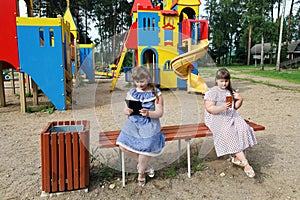 Chubby children are sitting on a bench on the playground