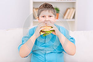 Chubby kid is eating a burger