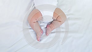 Chubby legs of little baby on white sheet background. Cute newborn sleeping