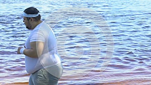 Chubby male and female running along waterfront, trying to lose weight, sport