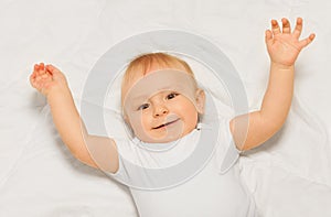 Chubby small baby with arms up on white blanket