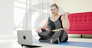 Chubby woman doing exercise by dumbbell and surfing internet