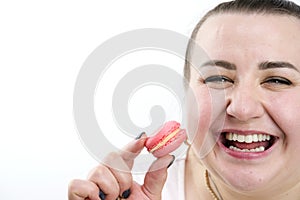 chubby woman eats delicious pink cherry raspberry strawberry macarons laughs on white background sincere laughter